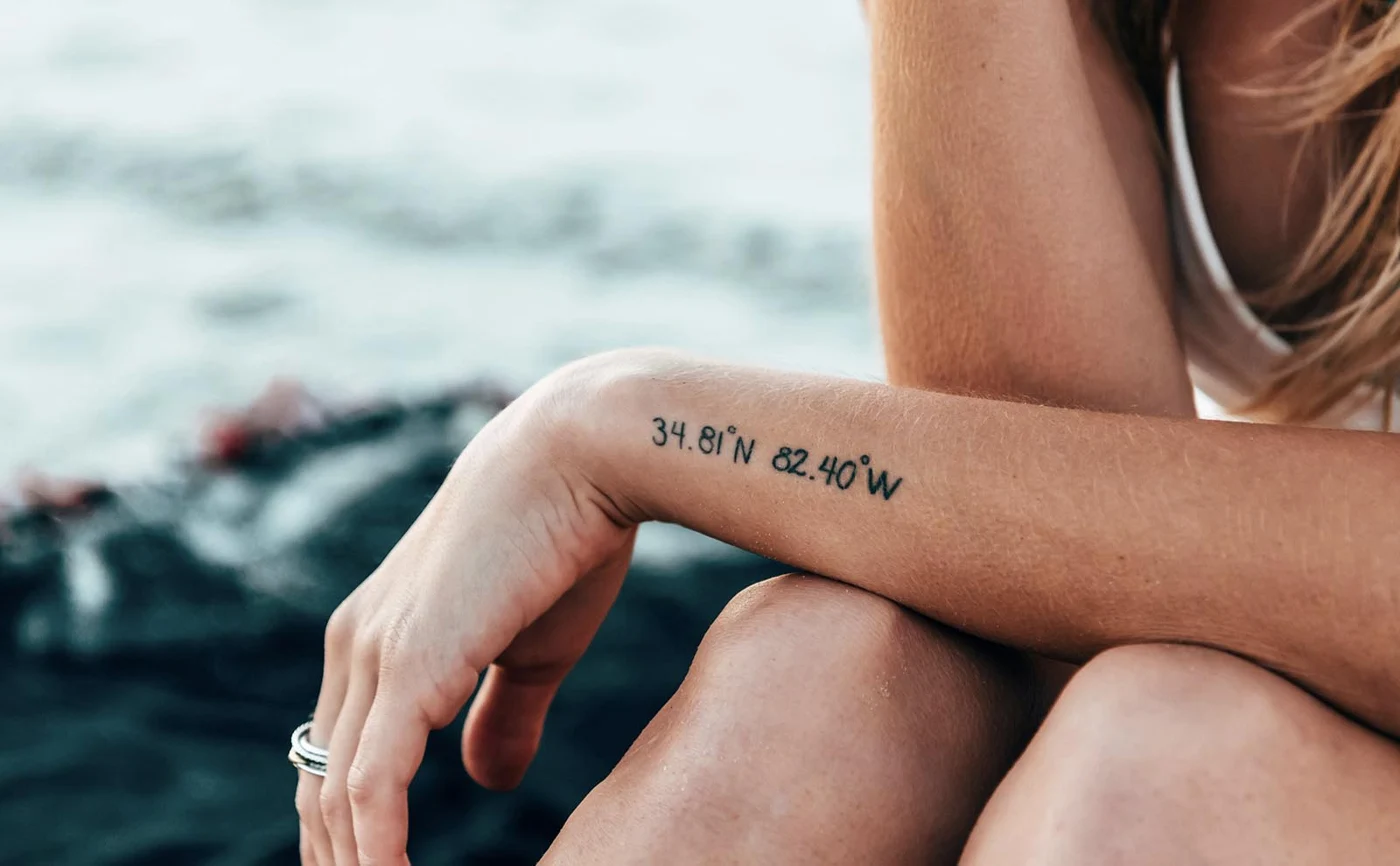 Close-up of a small wrist tattoo on a relaxed arm outdoors.